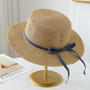 High-quality Raffia straw hat with elegant blue bow ribbon displayed on a gold stand