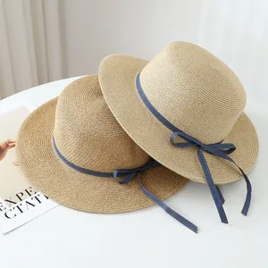 Detail view showing the woven texture of raffia straw hats with blue denim ribbons