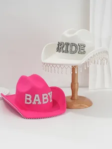 Close-up of pink and white cowboy hats with rhinestone BRIDE and BABY letters.