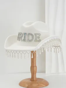 Detail view of white bride cowboy hat with iridescent rhinestone letters and pearl fringe