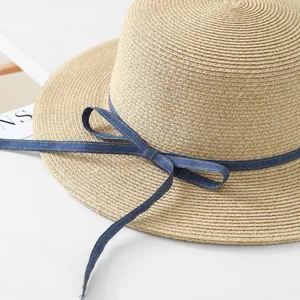 Close-up of raffia straw hat with blue denim bow detailing for summer sun protection.