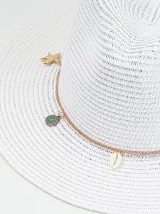 Detail van witte Panama strohoed met goudkleurige ketting met schelp en zeester versiering