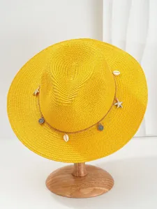 Detailopname van een gele Panama strohoed met schelp- en zeesterren decoratieve band