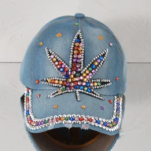 Detailaufnahme der hellblauen Denim-Kappe mit buntem Strass-Cannabisblatt-Design.