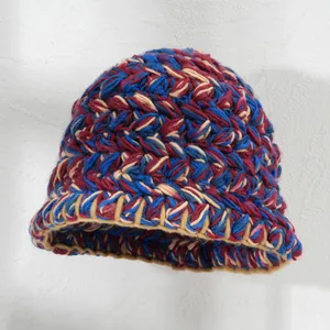 Primo piano di un cappello da pescatore in maglia colorata da donna in blu, rosso e beige