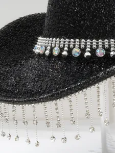 Close-up of a sparkly black cowboy hat featuring rhinestone fringe and jewel embellishments.