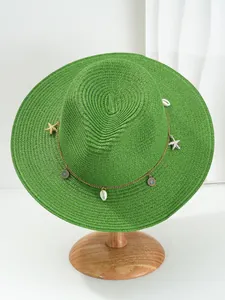 Groene Panama strohoed met schelpen en zeesterren bedels op een houten hoedenstander.