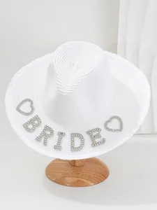 Λεπτομέρεια του "BRIDE" από στρας σε ένα λευκό ψάθινο καπέλο παραλίας.