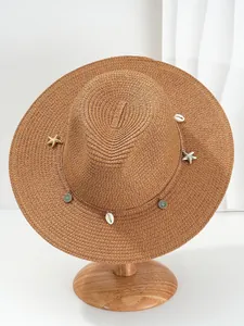 Detail van Panama strohoed met schelp en zeester bedeltjes aan een gouden ketting