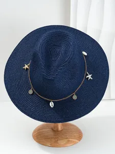 Detail van blauwe Panama strohoed met decoratieve ketting, schelp en zeester hangers aan band