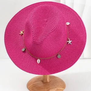 Fuchsia Panama strohoed met schelpen en zeesterren bedeltjes voor op het strand