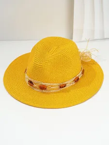 Detail view of a vibrant yellow Panama straw hat with amber beads and a woven band.