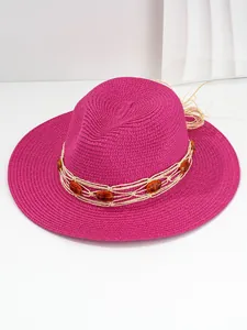 Detailed macro view of a vibrant fuchsia Panama straw hat decorated with amber beads