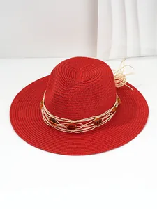 Detailed view of vibrant red woven straw Panama sun hat with amber beads decoration.