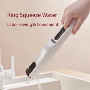 Hand squeezing water from a white handheld mini sponge mop over a bathroom sink.