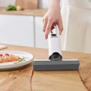 Detailed action shot of a white mini handheld sponge mop cleaning liquid on wooden table