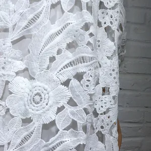 Vue macro détaillée de la dentelle florale blanche hydrosoluble pour une robe ajourée.