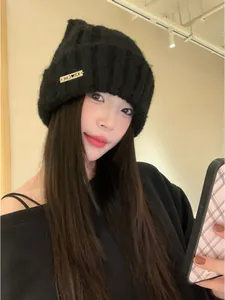 Detailed view of a black cat ear knit beanie worn by an Asian model in a warm room