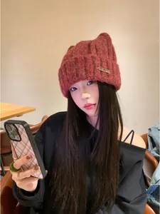 Close-up detail of cute reddish-brown knit cat ear beanie worn by model in cafe setting