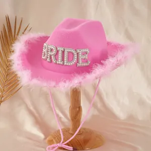 Detail of pink bride cowboy hat with feather trim and BRIDE rhinestone lettering.