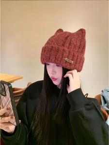 Girl wearing a cozy reddish-brown knitted beanie with cute cat ears in a cafe setting