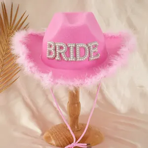 Close-up of pink bride cowboy hat with pearl BRIDE lettering and feather trim
