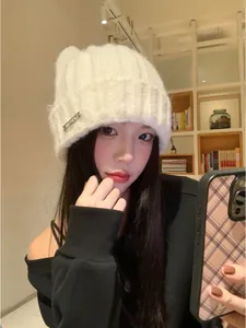 Cozy white winter knit beanie hat with cute cat ears design worn by a female model