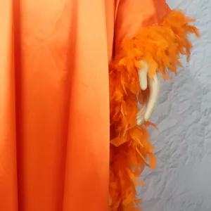 Nahaufnahme des orangefarbenen Kaftans mit luxuriösem Federbesatz an den Fledermausärmeln