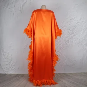 Detail eines orangefarbenen Satin-Kaftans mit Federbesatz und Fledermausärmeln