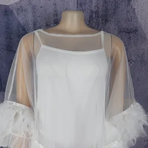 Detail shot of white mesh dress with feather trim on sleeves and inner camisole.