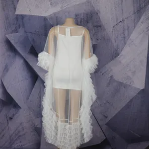 Close-up detail of white African fashion gown featuring sheer mesh and feather ruffles.