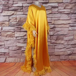 Detail des gelben Satin-Afrikanischen Kaftans mit Federbesatz und hohem Schlitz