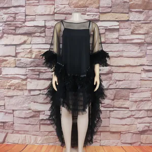 Close-up detail of black feather trim and tiered tulle ruffles on sheer mesh gown