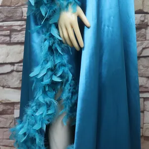 Nahaufnahme des blauen Satin-Afrikakleids mit elegantem Federbesatz und hohem Schlitz
