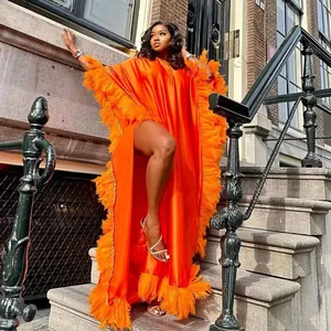 Detailansicht des orangefarbenen afrikanischen Kaftan-Kleides mit Federn und Schlitz