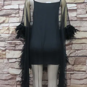 Detail of black mesh dress back showing feather sleeve trim and ruffle hem detail.