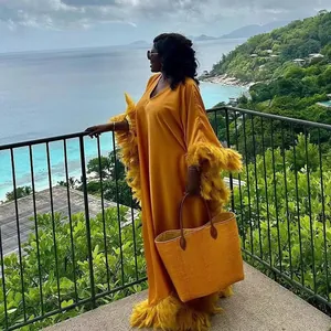 Detailansicht eines eleganten afrikanischen gelben Kaftan-Kleides mit Federbesatz-Deko