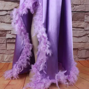 Detailansicht des lila Satin-Gewandes mit luxuriösem Federbesatz und hohem Beinschlitz.