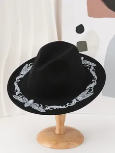 Macro view of black fedora featuring intricate white cicada embroidery on the brim