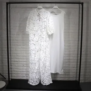 Vue détaillée d'une robe longue en dentelle blanche évidée avec fond de robe sur cintre.