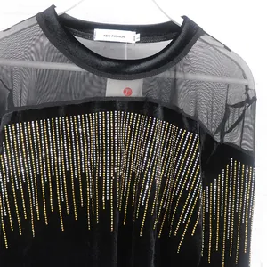 Detail of black velvet African top with mesh panels and shimmering gold rhinestone lines.