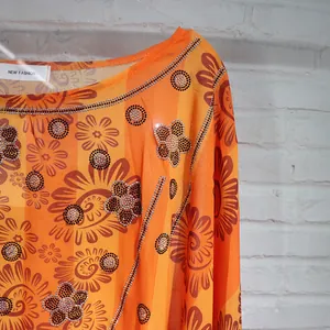 Close-up of African chiffon dress with floral print and rhinestone beading details