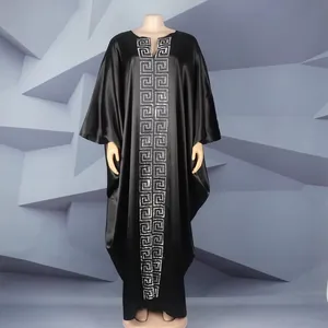 Close-up of elegant black satin African kaftan dress with rhinestone Greek key pattern.