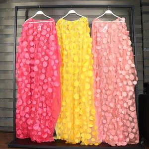 Detail of African maxi dresses with 3D floral embroidery in pink, yellow and peach colors.