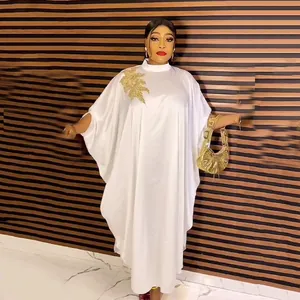 Detailed view of white African kaftan dress with gold embroidery and batwing sleeves.