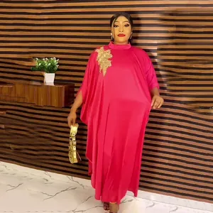 Detailed view of the gold rhinestone floral applique on a fuchsia African kaftan dress