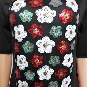 Detailed close-up showing vibrant floral sequin patchwork on a black African dress