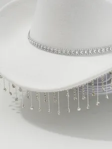 Detail van een witte vilten cowboyhoed met sprankelende strass-franjes en luxe afwerking