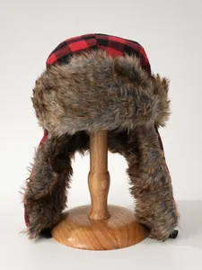 Close-up of red and black plaid trapper hat with fluffy faux fur on wooden stand