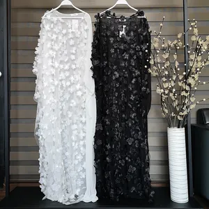 Gros plan de robes maxi élégantes blanches et noires avec broderie florale en 3D
